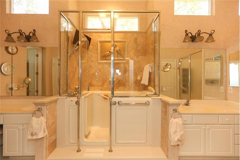 Owners bathroom has a glass-enclosed multi-feature, walk-in Jacuzzi & large illuminated glass door shower enclosure and tray cei