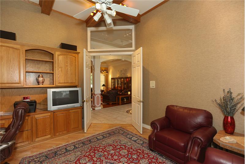 View of the living room and foyer from the den which has a coffered ceiling.
