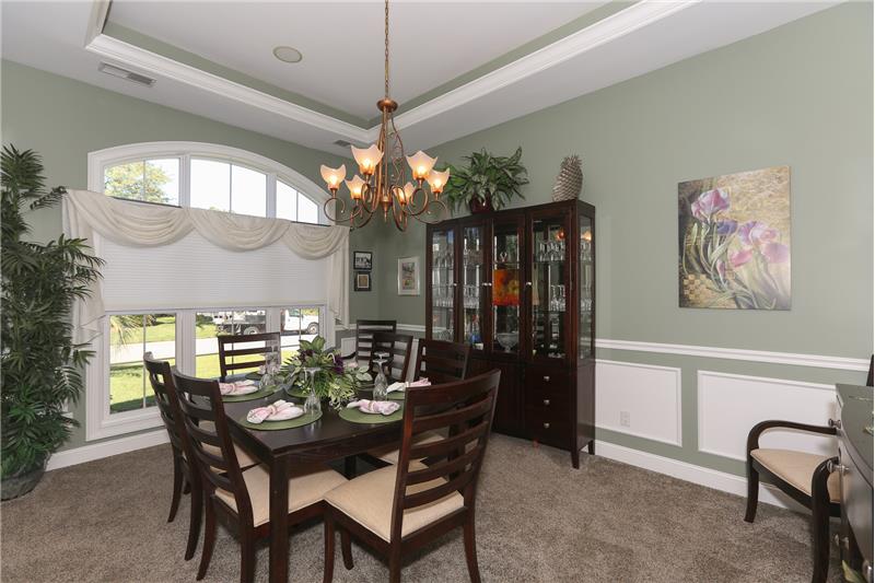 The dining room has a beautiful arched window and wainscoting.
