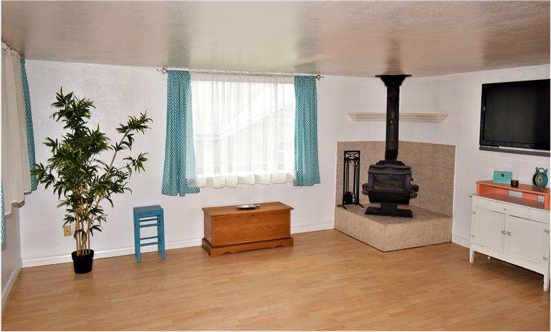 Living room with natural light galore, and cozy wood-burning stove with tile hearth.
