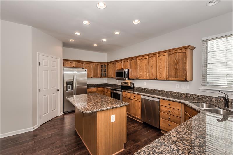 Kitchen offers new granite counters, refinished cabinets, new fixtures, new wide-plank hardwood floors, recessed lighting.