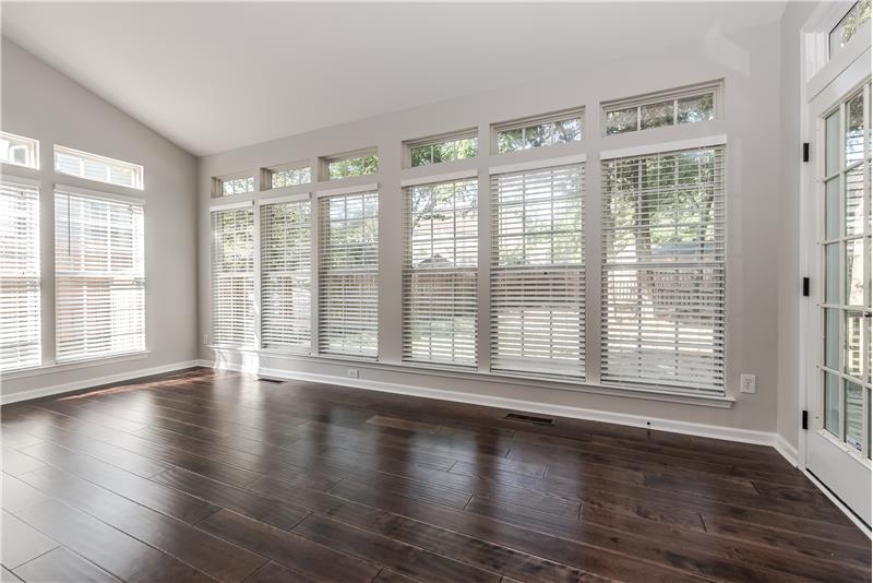 Sun room features new wide-plank hardwood floors, fresh neutral paint, new light fixture, new blinds, vaulted ceiling.