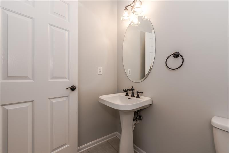 Powder room with new toilet, fixtures, light, fresh neutral paint, tile floor.