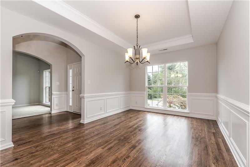 Elegant, formal dining room with new hardwood floors, new designer chandelier, French-style windows, trey ceiling, wainscoting.