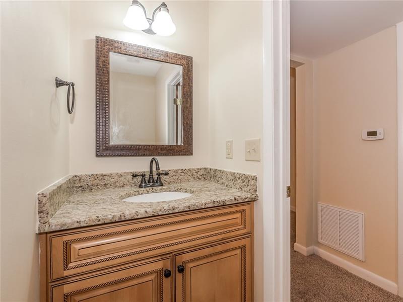 Powder room with new cabinet, granite counter, new mirror, light fixture and toilet.