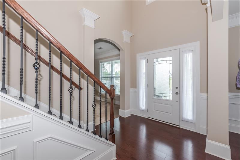 Dramatic two-story foyer features gleaming hardwood floors, front door with leaded glass and side light windows for lots of natu