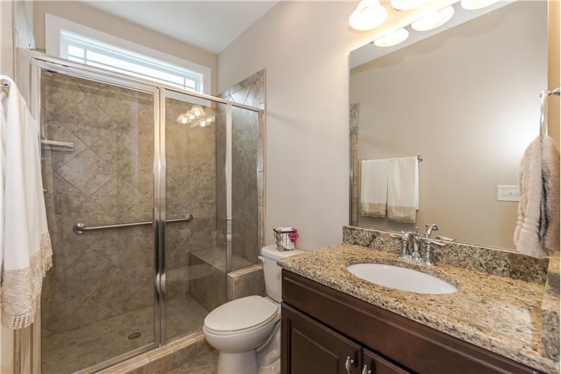 One of the home's full bathrooms with granite counters, tile surround and floors.