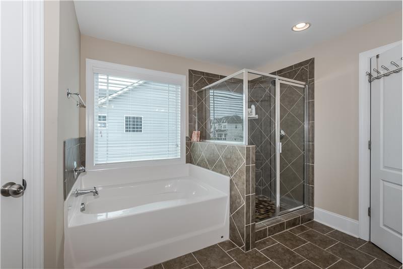 Spa-inspired master bathroom with deep soaking tub, separate shower, tile surround and floors.