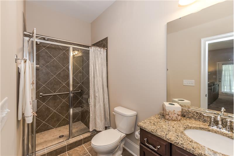 Full bathroom in basement with granite counters and tile floors/surround.