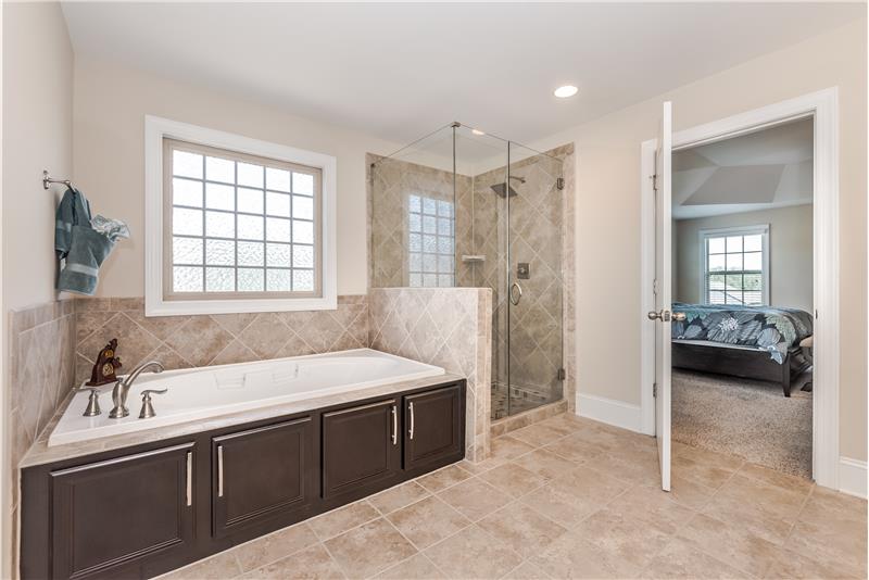 Master bath features tile floors and surround, large frameless shower with tile surround, whirlpool tub, private WC. Picture win