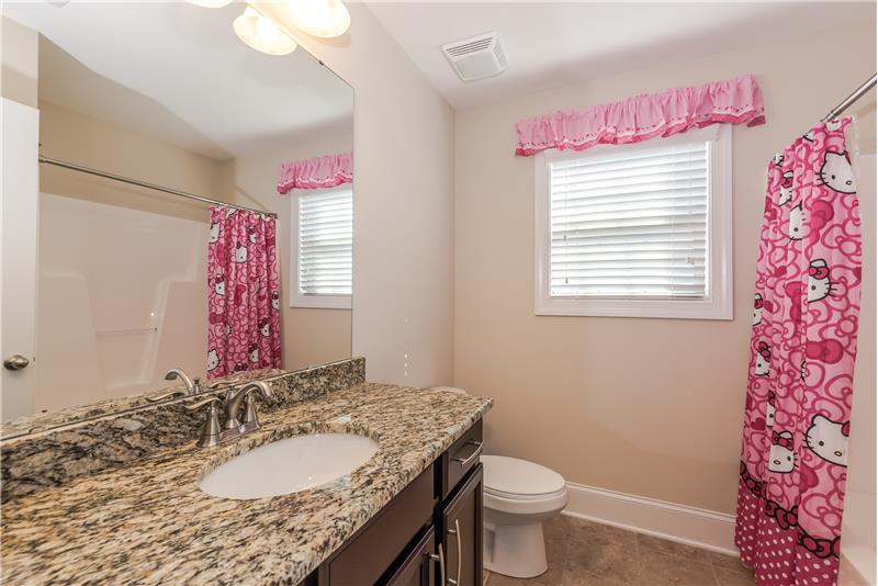 Bathroom shared by two of the secondary bedrooms features raised vanity with granite sink, tile floors, tub/shower combination.
