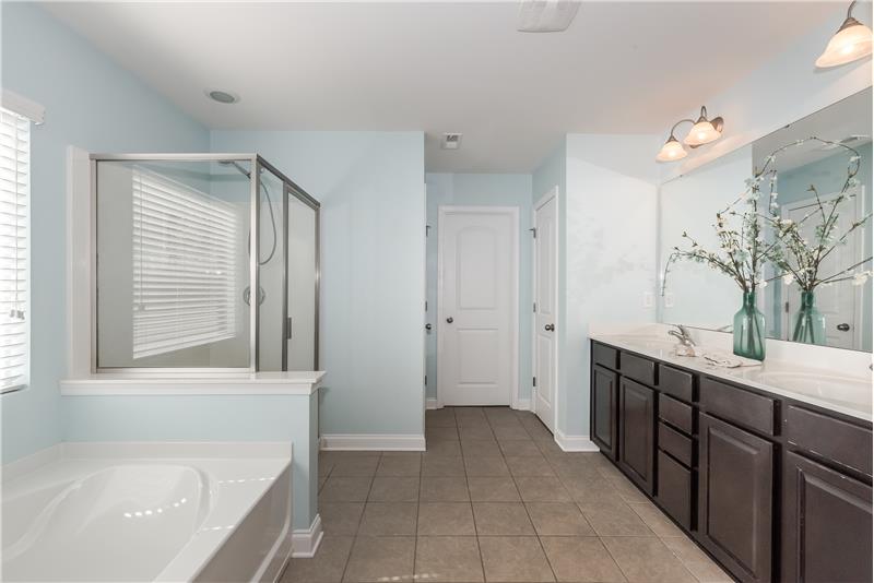 Expansive double sink vanity, soaking tub, separate shower, private WC, large walk-in closet.