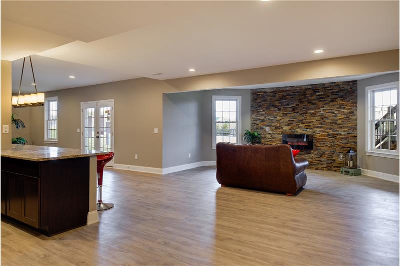 The basement is the perfect entertaining den...Rec room with stacked stone wall, decorative fireplace and recessed