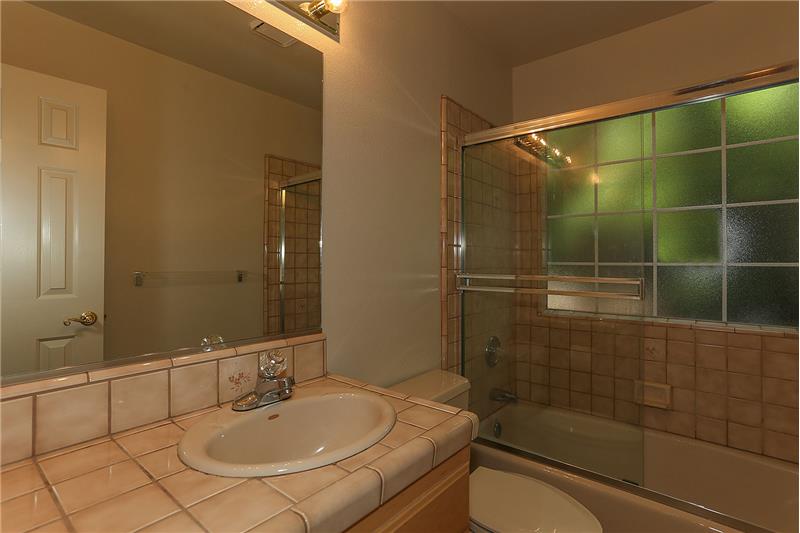 Guest Tiled Bathroom with glass enclosed Tub