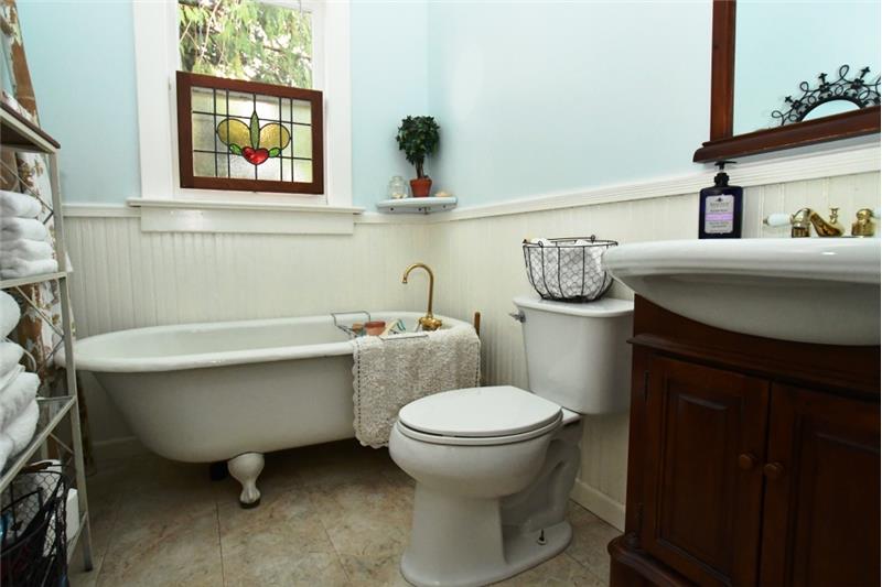 Main bathroom with authentic claw foot tub and wood wainscoting paneling.