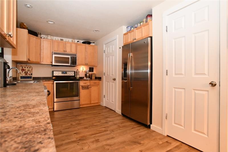 Kitchen has SS side-by-side fridge. Pantry door on right, utility closet door on left.