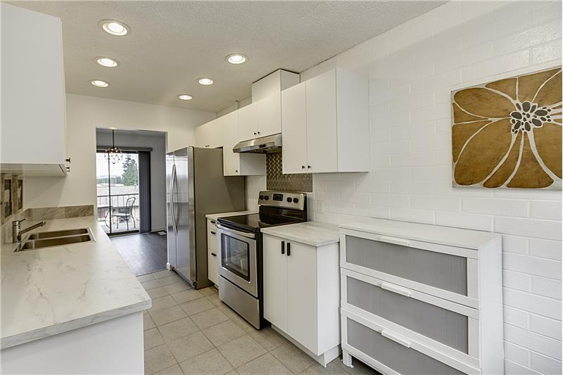 Remodeled Kitchen with New White Counter Tops, Back Splash, Tile Floor and Stainless Steel Appliances. Includes Breakfast Nook a