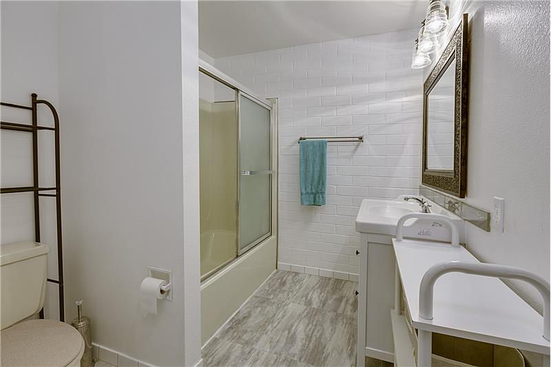 Remodeled Bathroom with New Floors, Vanity, Mirror and Light Fixture.